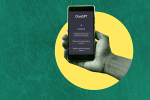 A man's hand holds a mobile phone which displays the ChatGPT homepage