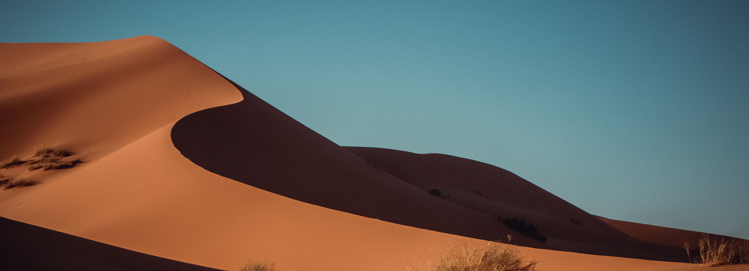 an image of a red sand dune against a blue sky