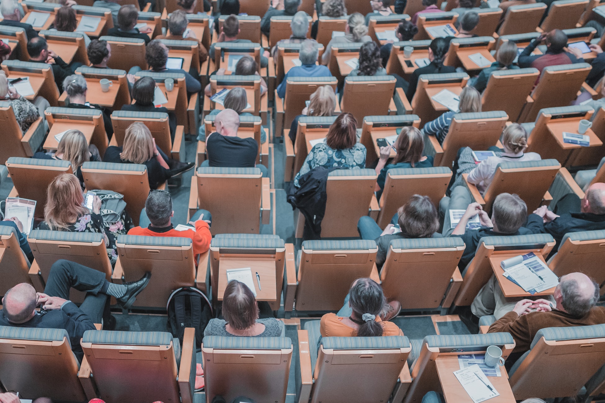 a birdseye view of a university lecture theatre with people sitting in chairs.